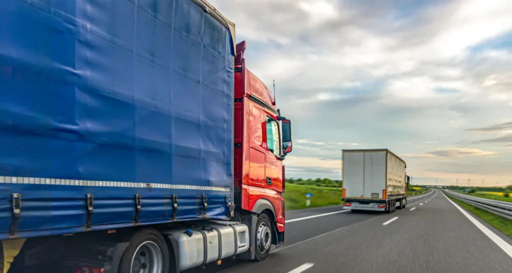 Ciężarówki z naczepami jadące autostradą w transporcie towarów między krajami
