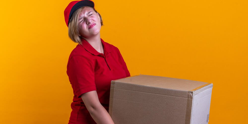 Kobieta kurierka z ciężką przesyłką