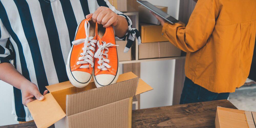 Kobieta pakująca buty do kartonu do przesyłki kurierskiej