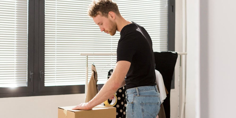 Mężczyzna pakujący przesyłkę z ubraniami
