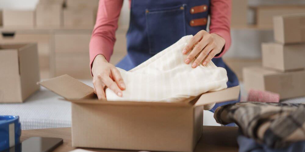 Kobieta pakująca ubrania do kartonu